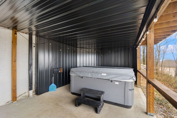 Un espace extérieur abrité comprenant un jacuzzi, un petit tabouret et un balai bleu.