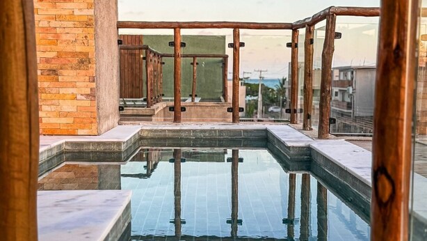 Μια πισίνα στην ταράτσα, με ξύλινο δάπεδο και τοίχο από τούβλα.