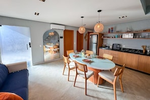 A modern kitchen with a dining area, wooden cabinets, and pendant lighting.