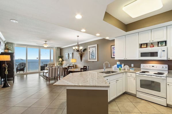 Una cocina amplia con una isla grande, armarios blancos y vistas al exterior.
