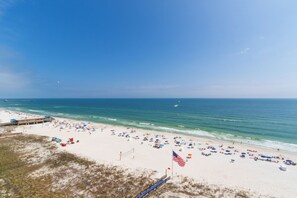 Ein Strand mit einer Holzpromenade, feinem Sand und einer Flagge.