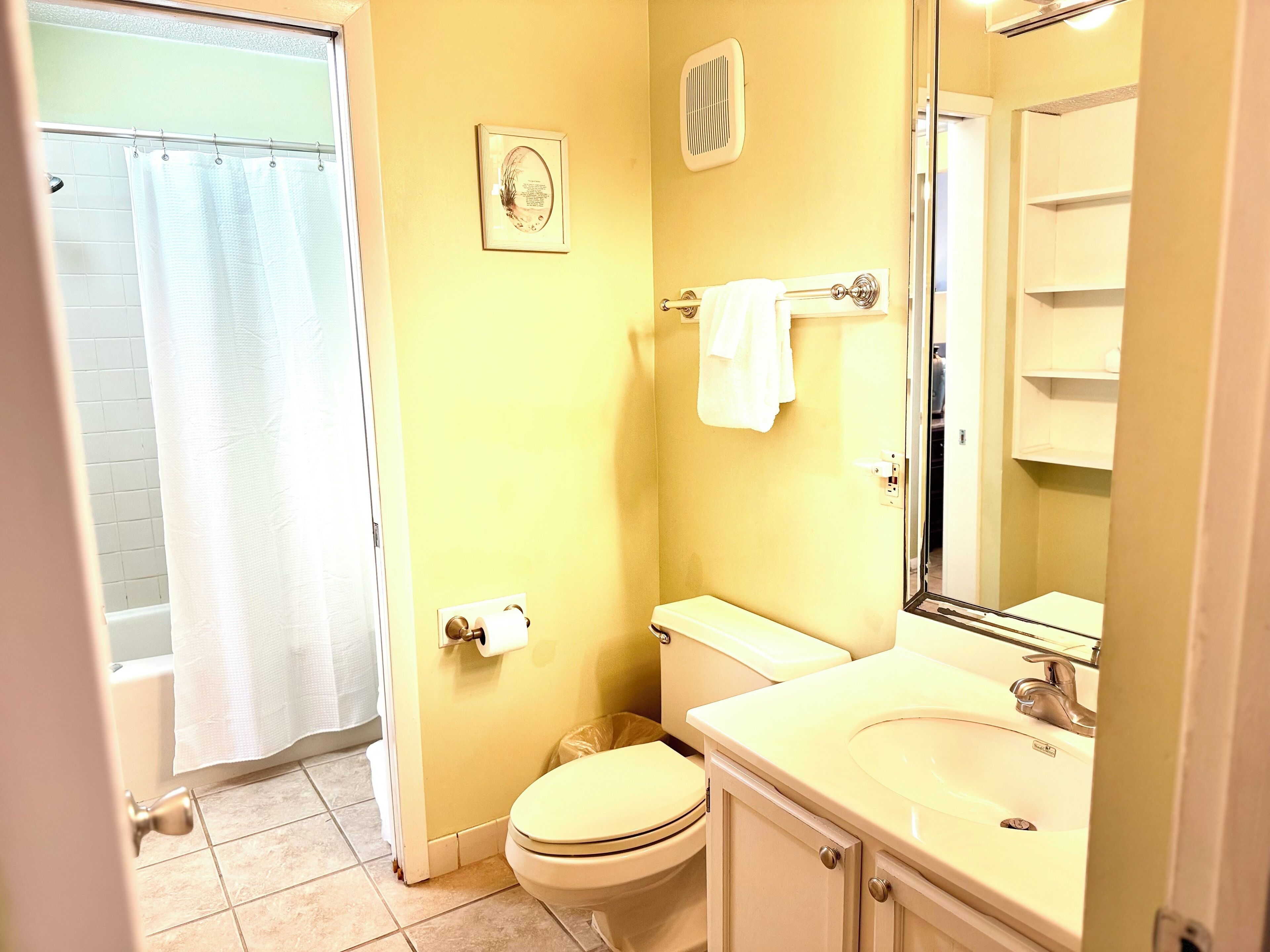 Un baño con inodoro, lavamanos y cortina de ducha.