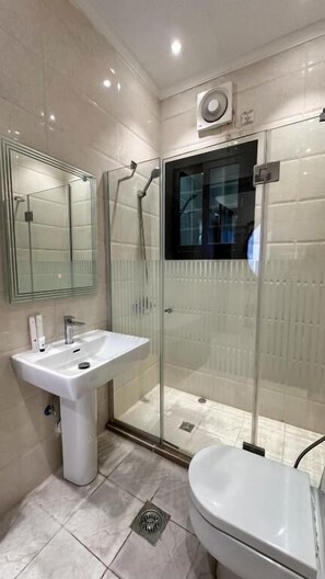 Une salle de bain moderne avec une douche à parois de verre, un lavabo sur colonne et des toilettes.