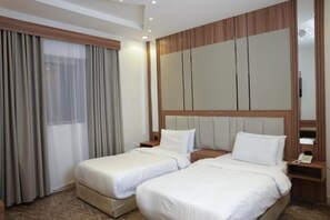 A hotel room with two beds, a large mirror, and a wooden headboard. - Malath Homes Aparthotel  (Jeddah)
