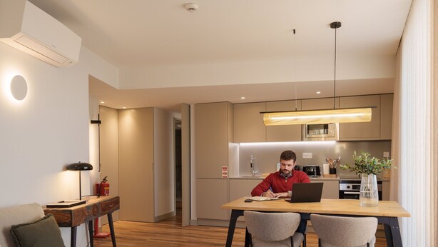 A modern kitchen with a dining area, a sofa, and a laptop on the table. - Feel Porto Firmeza Coworking Flat 1 3 (Porto)