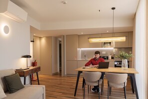 A modern kitchen with a dining area, a sofa, and a laptop on the table. - Feel Porto Firmeza Coworking Flat 1 3 (Porto)