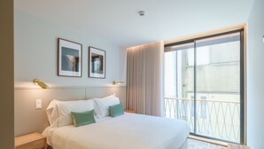 A hotel room with a large bed, two framed pictures on the wall, a nightstand, and a view of the outside balcony. - Feel Porto Firmeza Coworking Flat 1 3 (Porto)