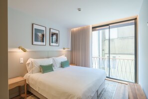 A hotel room with a large bed, two framed pictures on the wall, a nightstand, and a view of the outside balcony. - Feel Porto Firmeza Coworking Flat 1 3 (Porto)