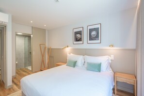 Un dormitorio con una cama grande, dos mesitas de noche, una lámpara de pie y cuadros enmarcados en la pared.