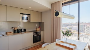 Una cocina moderna con microondas, horno y tostadora integrados. Hay una mesa de comedor con un jarrón de flores y una bandeja.