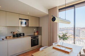 Una cocina moderna con microondas, horno y tostadora integrados. Hay una mesa de comedor con un jarrón de flores y una bandeja.