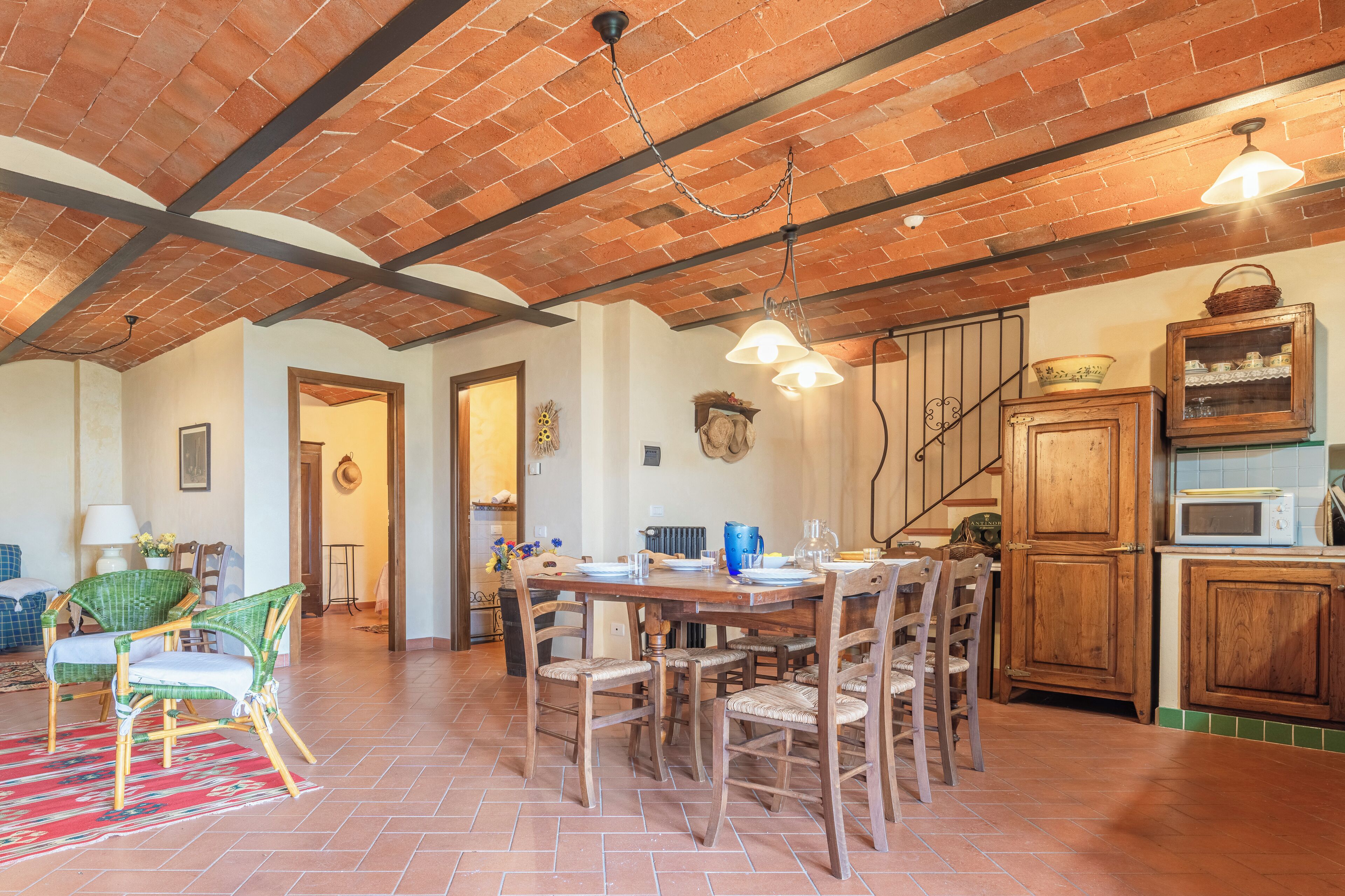 Un comedor amplio con techo de ladrillo, mesa y sillas de madera.