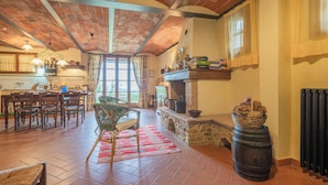 A spacious living area with a high ceiling, exposed brickwork, a fireplace, and a dining area with wooden furniture. - Casa Viola Pool Wifi Montaione (Montaione)