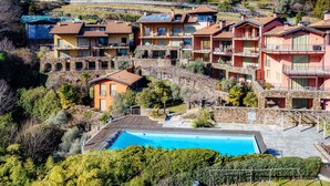 Una zona residencial en una ladera con varias casas de dos pisos, una piscina y un muro de contención de piedra.