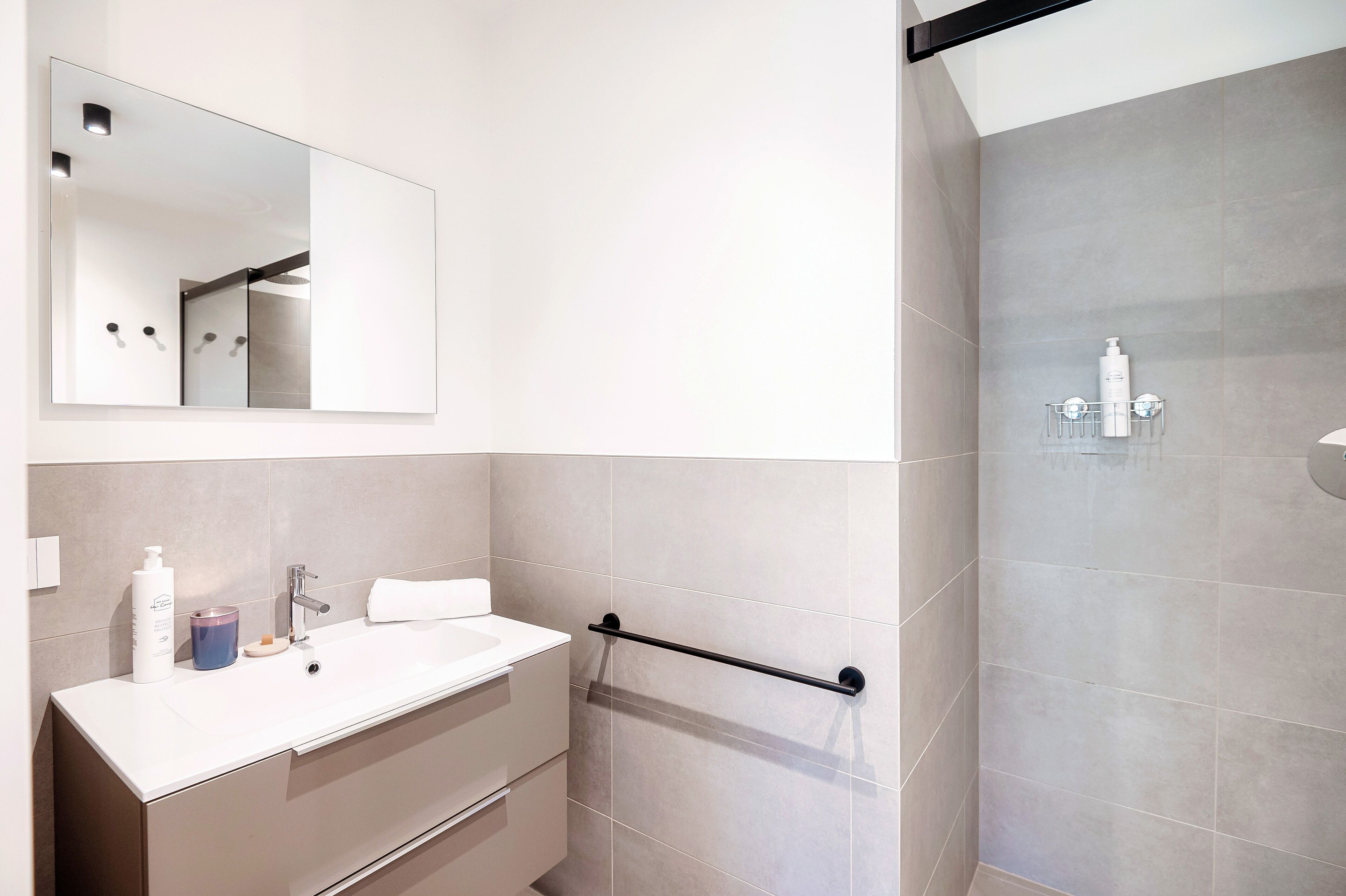 Un baño moderno con un tocador blanco, un espejo grande y un perchero para toallas.
