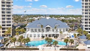 A large hotel with a swimming pool, multiple balconies, and a view of the surrounding area.