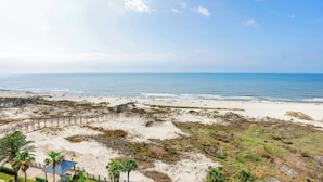 A beach with a wooden boardwalk, palm trees, and a clear view of the ocean.