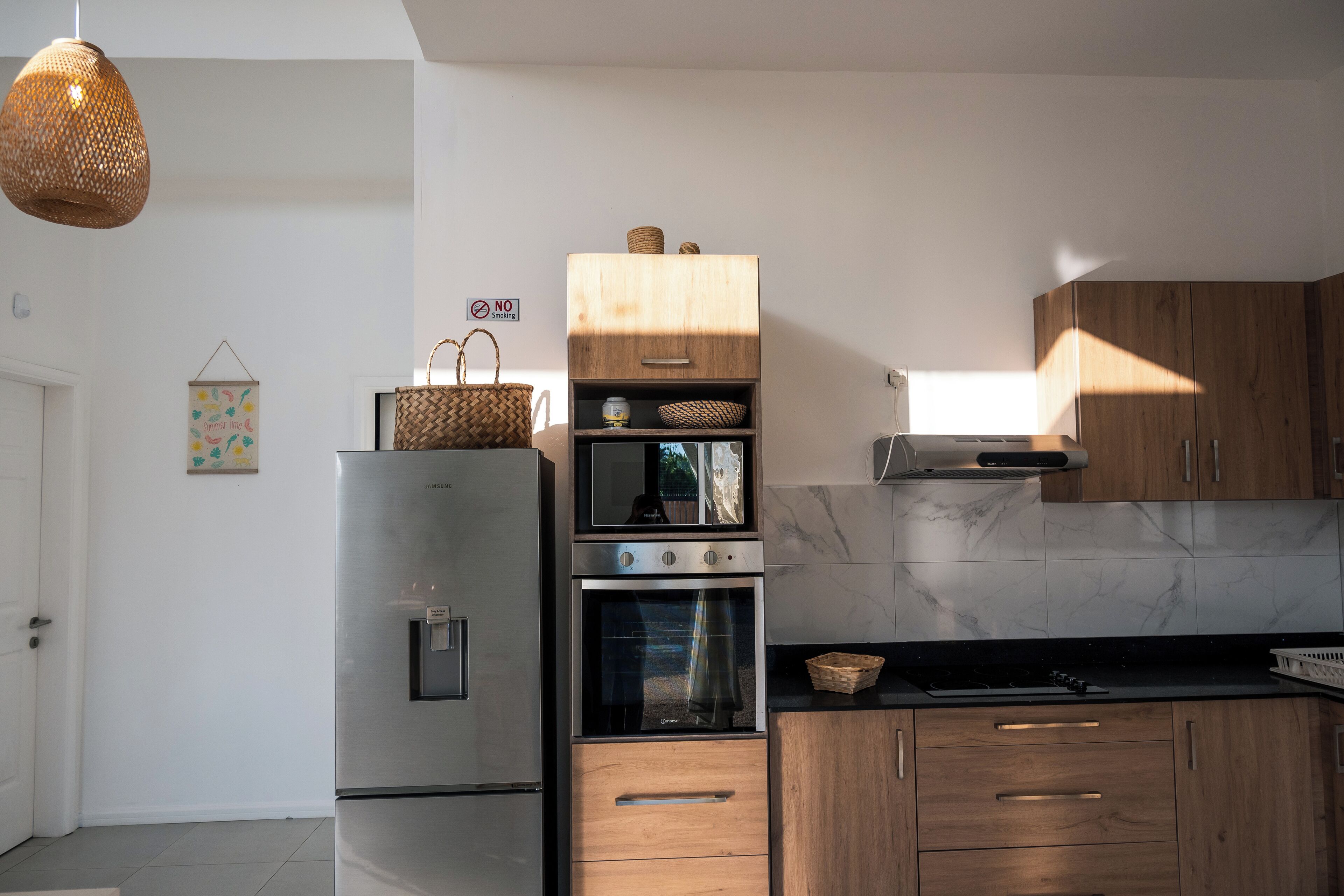 Eine moderne Küche mit Edelstahlgeräten, Holzschränken und einer Pendelleuchte.