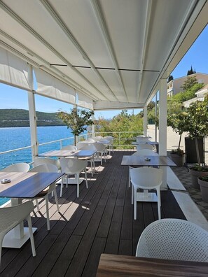 Un espace extérieur aménagé avec des tables et des chaises, offrant une vue sur un plan d’eau.