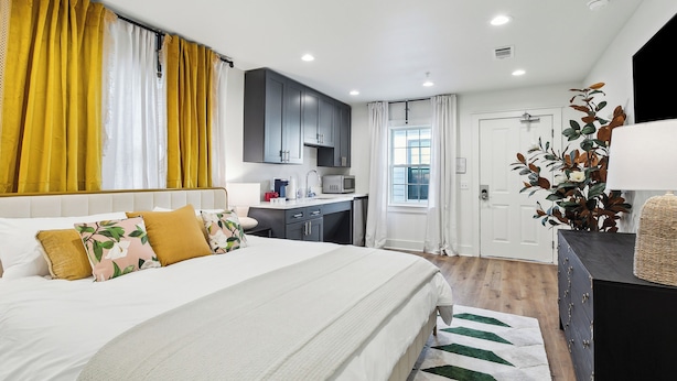 Een slaapkamer met een groot bed, een bureau en een kitchenette.