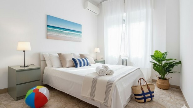 A neatly arranged bedroom with a bed, bedside lamps, a beach-themed painting, a beach ball, and a plant. - Cycling Riviera apartment (Imperia)