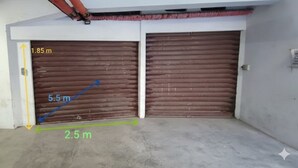A garage with two closed garage doors, marked measurements, and a concrete floor. - Cycling Riviera apartment (Imperia)
