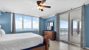 Une chambre avec un lit, un ventilateur de plafond, une commode et une vue sur le balcon.