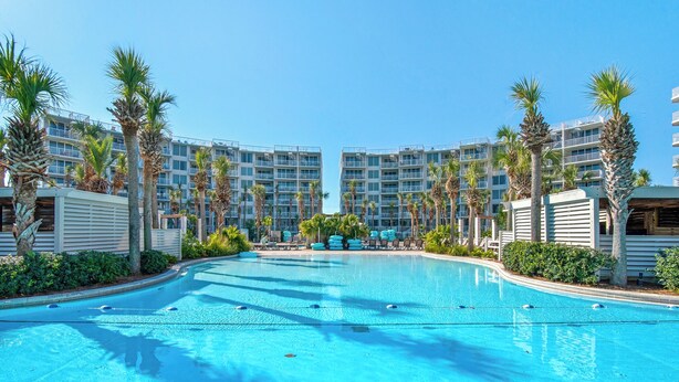 Une piscine entourée de palmiers et de bâtiments modernes.