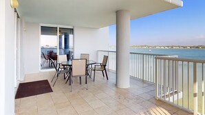 Un balcon donnant sur la mer, une table avec des chaises et une porte menant à un espace intérieur.
