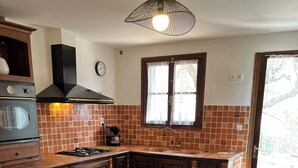A kitchen with a gas stove, sink, and a dining table with chairs.