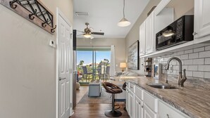 A kitchen with white cabinets, a marble countertop, a modern faucet, and a ceiling fan. - ☀️30A Private Beach Access-Pool-Inn at Seacrest 309- Somewhere in the Sun☀️ (Inlet Beach)