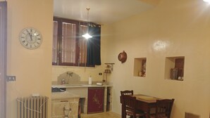 A compact kitchen with a dining area, a clock, and a radiator. - Luxury studio apartment in farmhouse (Sannicola)