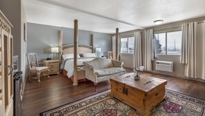 Een slaapkamer met een bed, een houten kist, een stoel, een bureau en een raam met gordijnen.