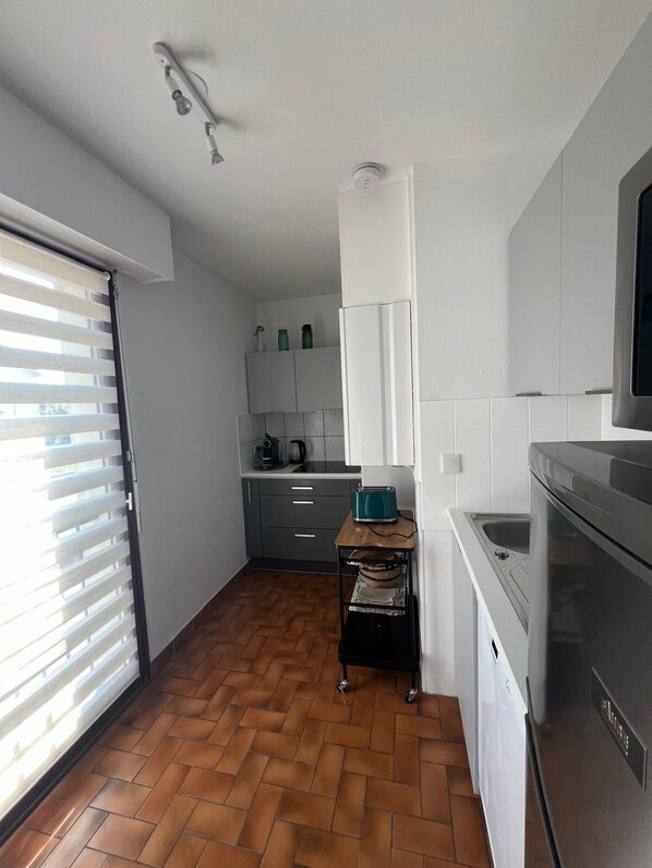A modern kitchen with white cabinets, a stainless steel refrigerator, and a herringbone-patterned floor.