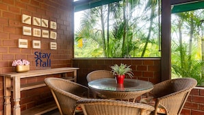 A cozy outdoor seating area with wicker furniture, a glass table, and a view of lush greenery through a window. - Casa de Campo Familiar em Gravata 065D (Gravata)