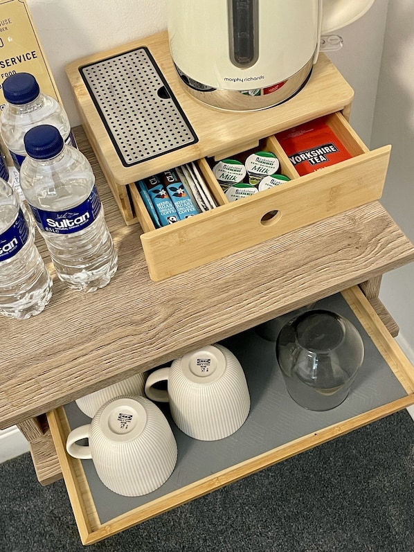A wooden tray with a kettle, water bottles, tea, and coffee containers. - Griffin House Hotel (London)