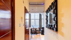 A hallway with a wooden door, a wall-mounted shelf, and a dining area with chairs and a table. - Griffin House Hotel  (London)