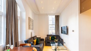 A modern living room with two sofas, a glass coffee table, and a dining table. - Griffin House Hotel  (London)