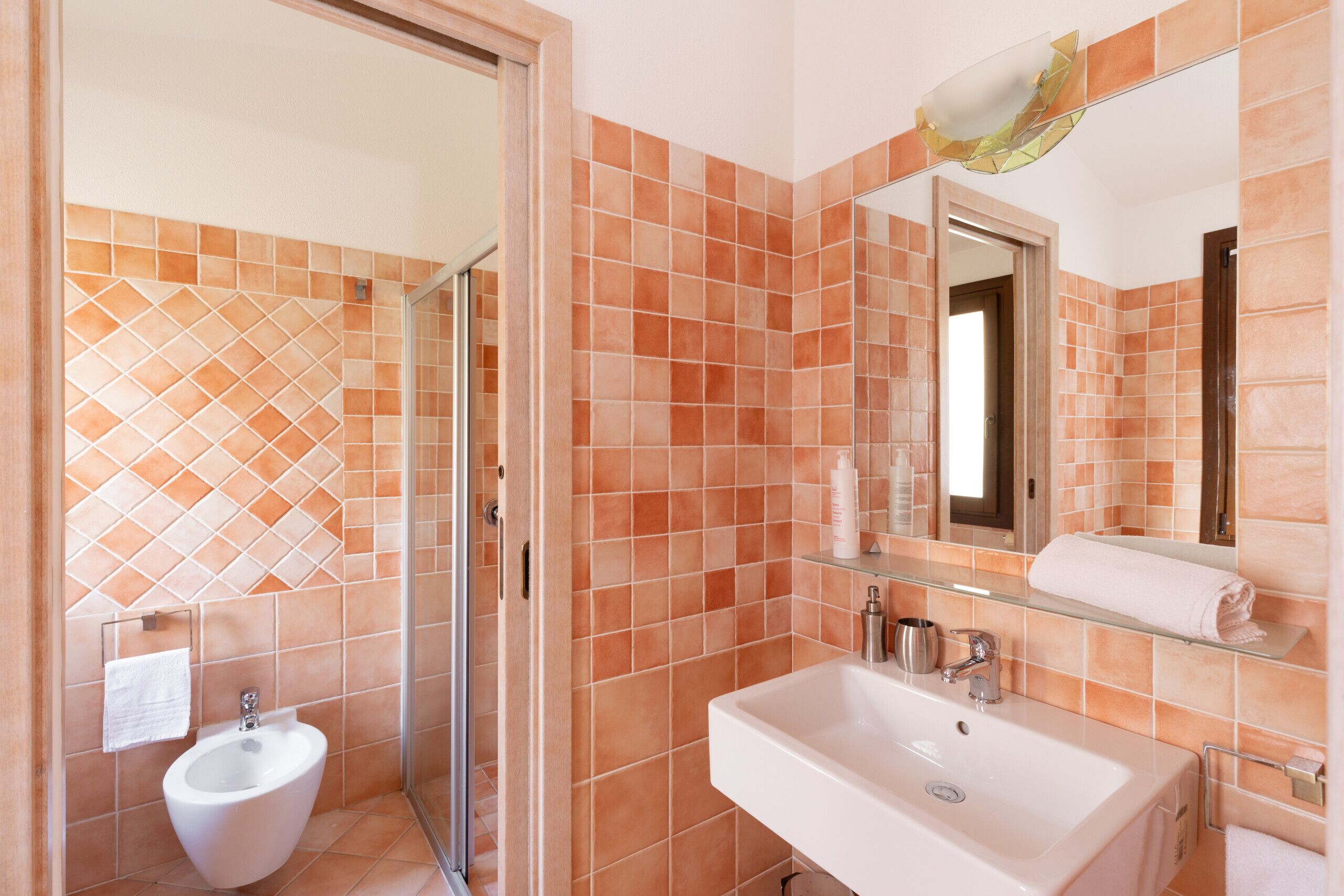 A bathroom with a bidet, a sink, and a glass shower enclosure.