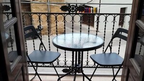 A balcony with a round table and two chairs, a metal railing, and a view of buildings in the background. - DE MEO GUEST HOUSE APPARTAMENT (Castellammare del Golfo)