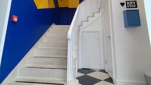 A staircase with a geometric wall design, a key drop box, and a fire alarm. - East Village 1-Bed Penthouse | Roof Terrace (Belfast)