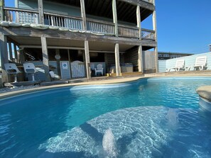 A pool area with a wooden deck and lounge chairs.