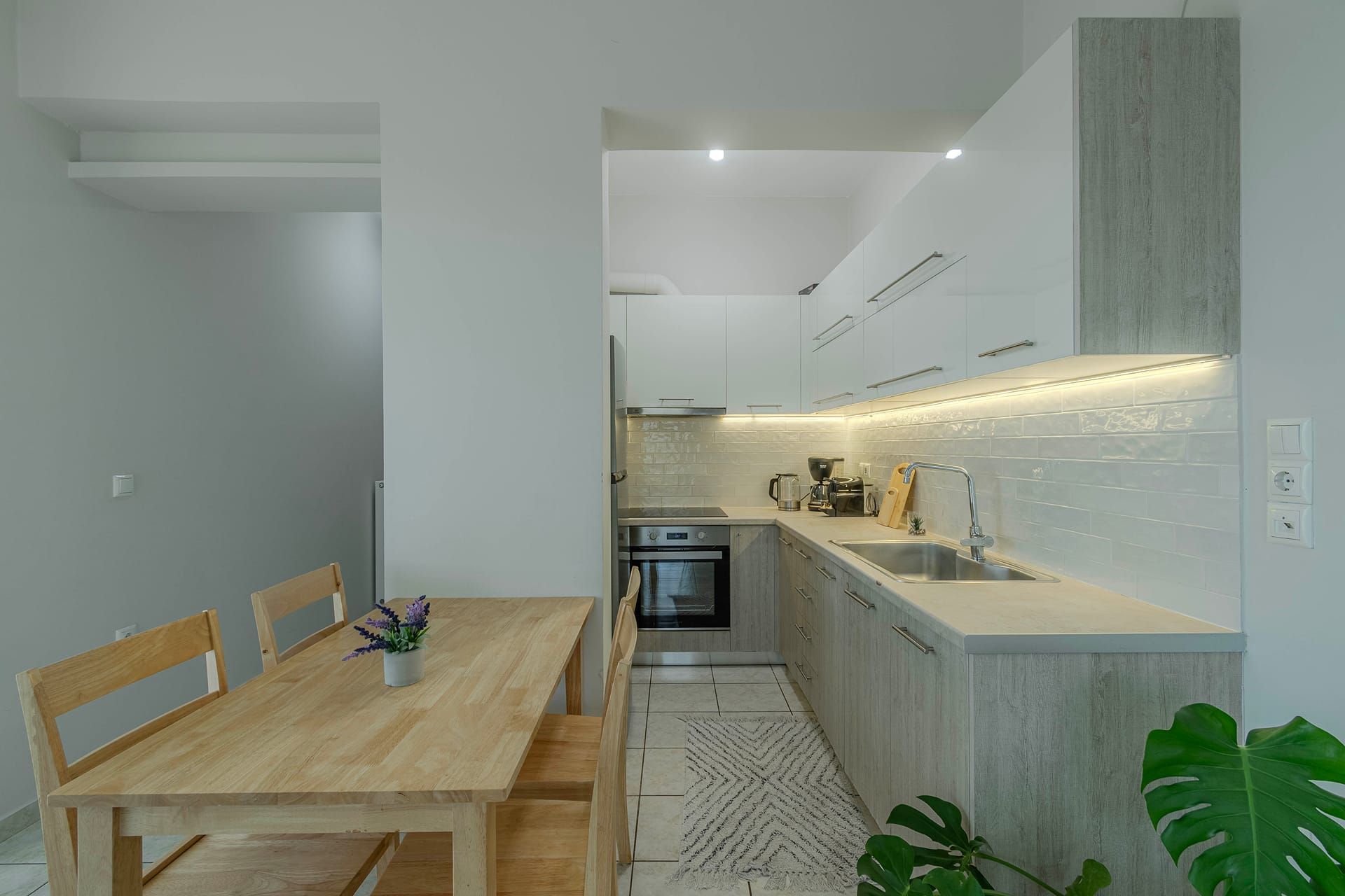 Una cocina moderna con horno empotrado, cafetera y lavamanos.