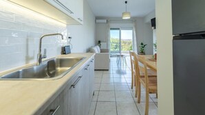 A modern kitchen with a large sink, wooden dining table, and chairs. - Joyful Guest House 2 Gaia by 8essentially (Galatas)