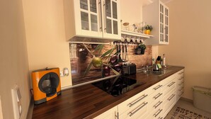 A modern kitchen with wooden cabinets, a built-in oven, and a coffee machine. - KRK Enjoy waterfalls, sun, beach and sea: Domicile Sunce Gudiča (Skradin)