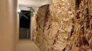 A corridor with a textured stone wall, a tiled floor, and a metal railing at the end. - KRK Enjoy waterfalls, sun, beach and sea: Domicile Sunce Gudiča (Skradin)
