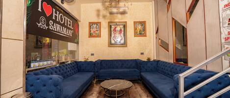 Eine Hotelhalle mit einem blauen, modularen Sofa, einem runden Tisch und einer Kronleuchter.