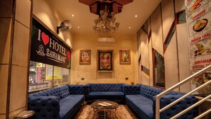 A hotel lobby with a blue sectional sofa, a chandelier, framed artwork, and a sign reading "I ♥ HOTEL SAWAMANI". - Hotel Sawamani and Restaurant (Danta Ramgarh)