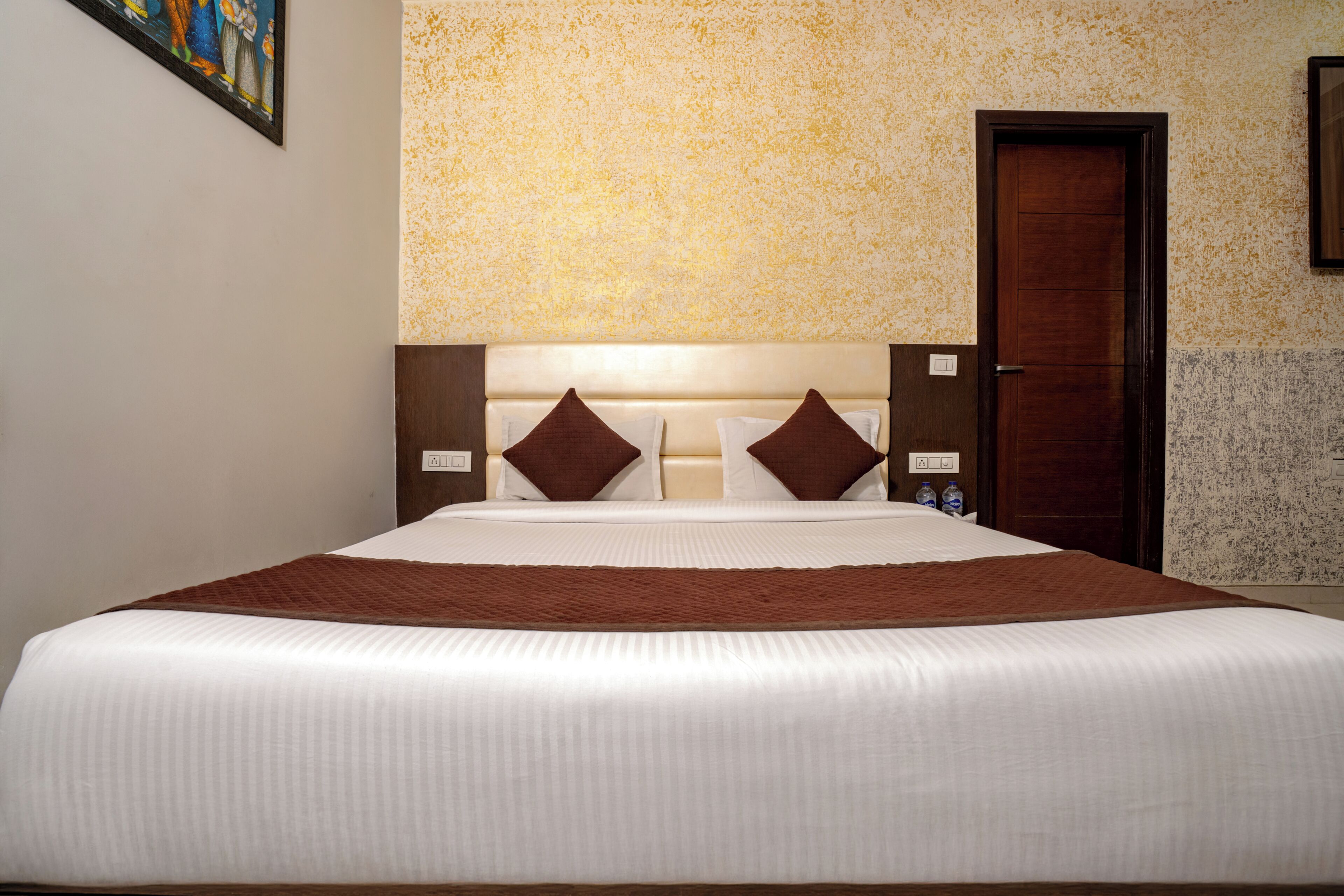 Ein Hotelzimmer mit einem großen Bett, einem hölzernen Kopfteil und einer Tür.