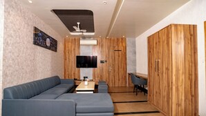 A modern living room with a sectional sofa, a flat-screen TV, a ceiling fan, and wooden cabinetry. - Hotel Sawamani and Restaurant (Danta Ramgarh)